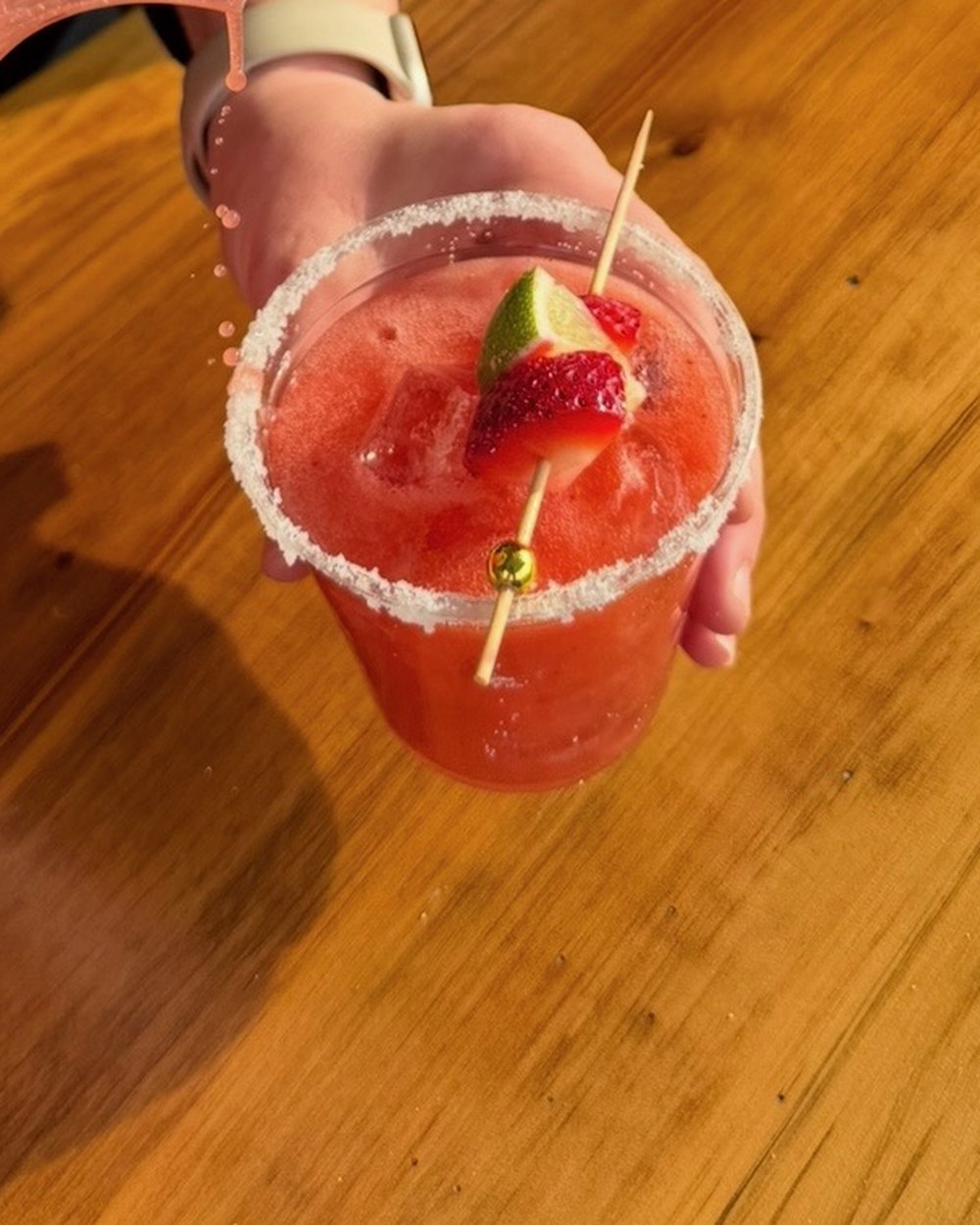 Strawberry margarita with a salted rim, fresh strawberry and lime garnish