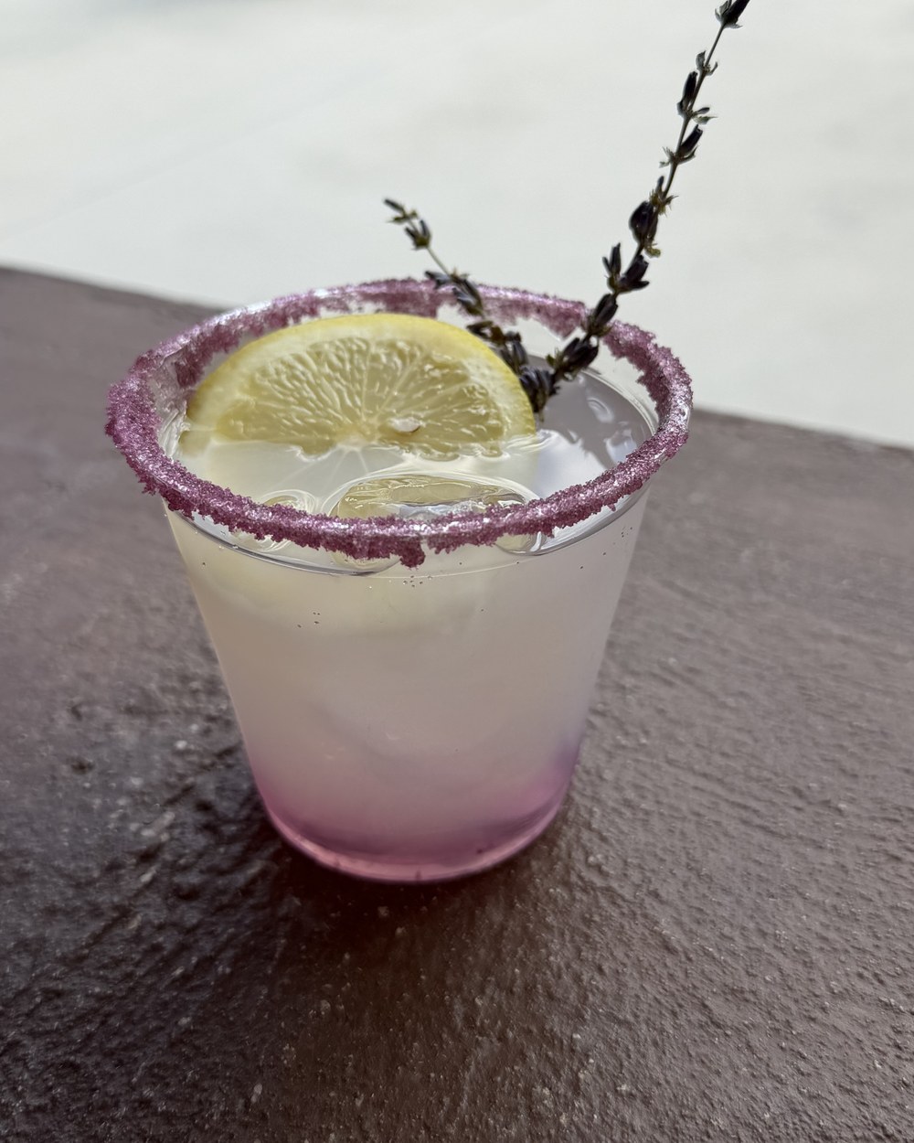 Lavender lemon drop with a lavender-sugar rim, lemon wheel and fresh lavender sprig