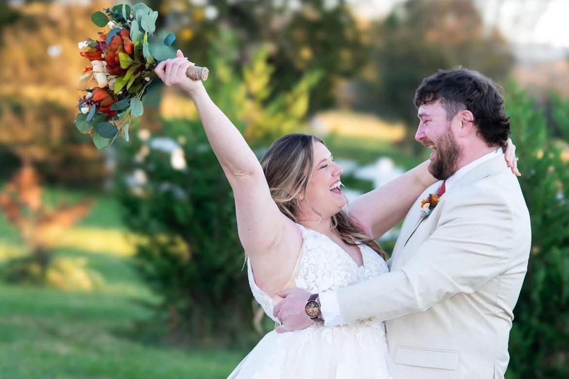 Newlyweds laughing, bride raising her bouquet